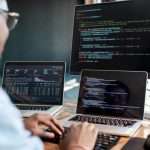 Programmer-writing-code-looking-at-monitors-768×399